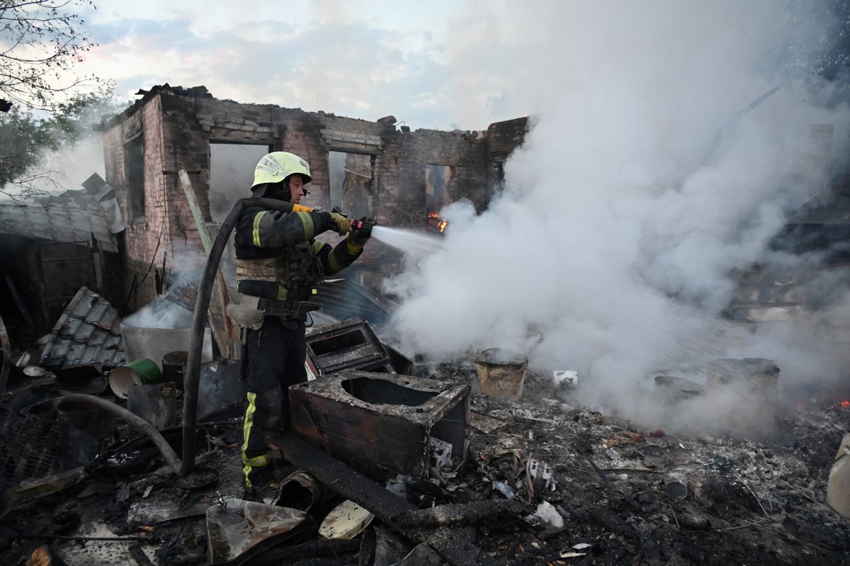 Firefighters put out a fire in a private house after a Russian drone attack in the suburbs of Kharkiv, on May 21, 2024, amid the Russian invasion in Ukraine. (Photo by SERGEY BOBOK / AFP)