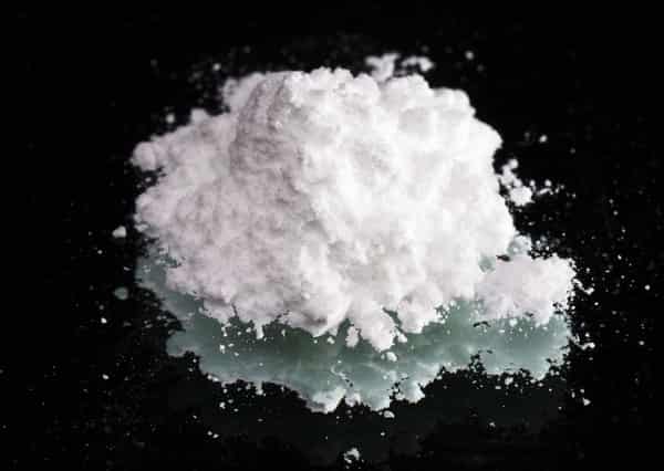Cocaine drugs heap on a black mirror, close up view