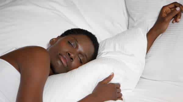 sb10064726e-001 BLACK Woman sleeping on bed in hotel room, close-up
