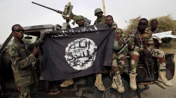 FILE PHOTO: Nigerian soldiers hold up a Boko Haram flag that they had seized in the recently retaken town of Damasak, Nigeria