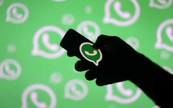 FILE PHOTO: A man poses with a smartphone in front of displayed Whatsapp logo in this illustration