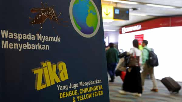 Airline passengers walk past a banner about the Zika virus shortly after landing from Singapore at Soekarno-Hatta airport in Jakarta