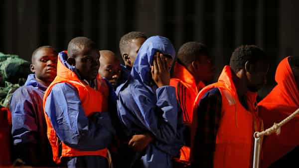 Migrants wait to disembark from a rescue boat after arriving at the port of Malaga