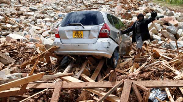 FILE PHOTO: A man gestures next to his car after it was swept into debris left by Cyclone Idai in Chimanimani, Zimbabwe