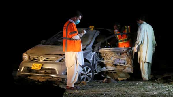 Members of the bomb disposal unit survey a damaged vehicle at the site after a blast near a mosque in Quetta,
