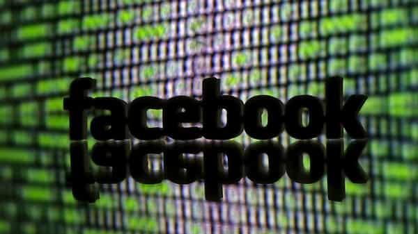 FILE PHOTO: 3D printed Facebook logo is seen in front of a displayed cyber code