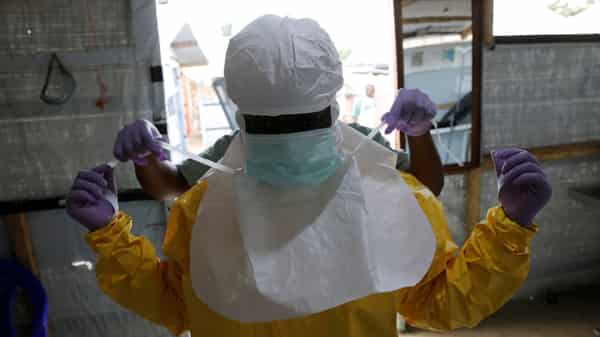 FILE PHOTO: A health worker puts on Ebola protection gear before entering the Biosecure Emergency Care Units at the Alima Ebola treatment centre in Beni
