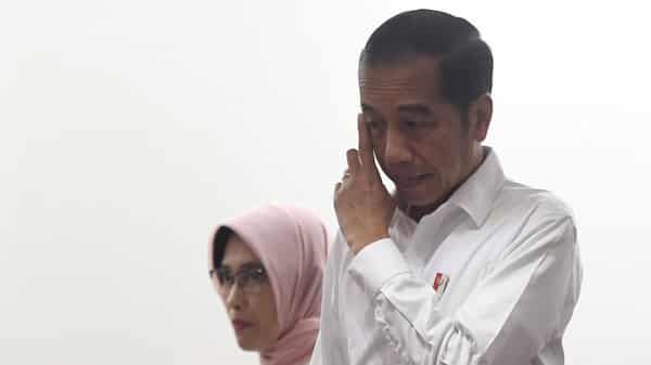 Indonesian President Joko Widodo gestures as he arrives with Sripeni Inten Cahyani, who is PLN’s acting CEO, during a visit at PT Perusahaan Listrik Negara (PLN) headquarters after a major power blackout in Jakarta
