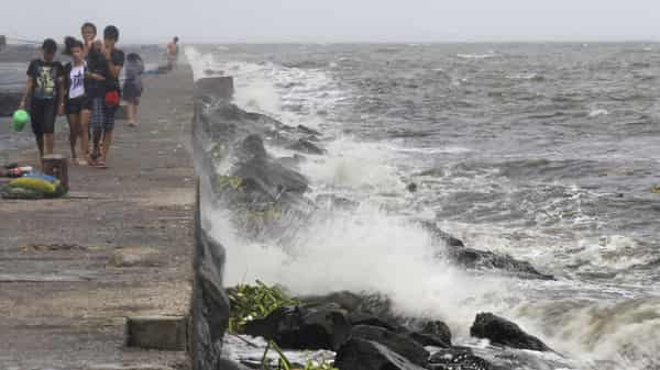 Youth walk on breakwater where rough waves caused by Typhoon Kalmaegi, also called Luis, are crashing, at Manila Bay
