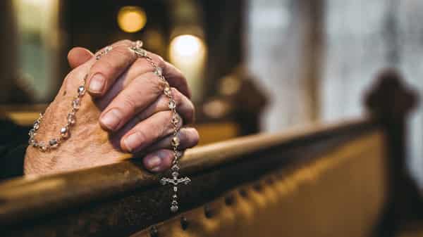 Praying hands with rosary in church