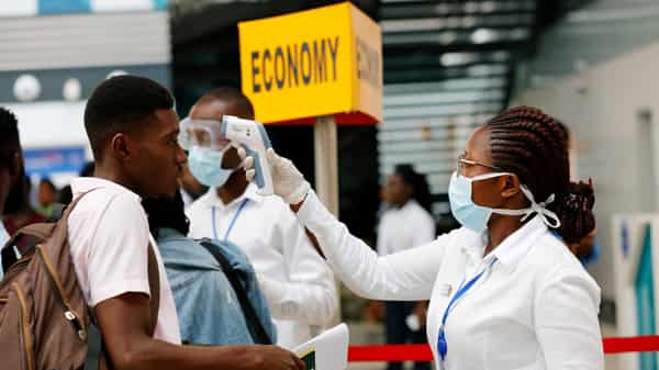 FILE PHOTO: A health worker checks the temperature of a traveller as part of the coronavirus screening procedure at the Kotoka International Airport in Accra,