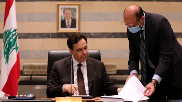 Lebanon’s Health Minister Hasan talks to Lebanon’s PM Diab during a cabinet meeting at the government palace in Beirut