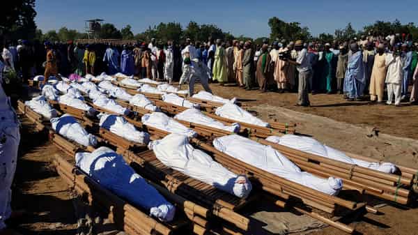 Men gather near dead bodies of people who were killed by militant attack, during a mass burial at Zabarmari