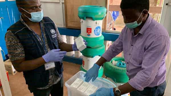 Workers from the World Health Organization inspect Ebola vaccines stored in an Arktek ultra-cold vaccine storage cylinder seen in the background in Mbandaka