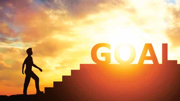 Man standing in front of stairs with “goal” writing on top.
