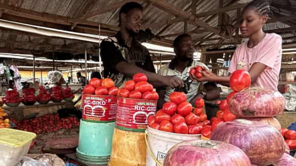 Farouk Dalhatu, a tomatoes seller attends to buyer in a community market of Agodo in Lagos,