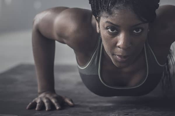Black woman doing push-ups in dark gym