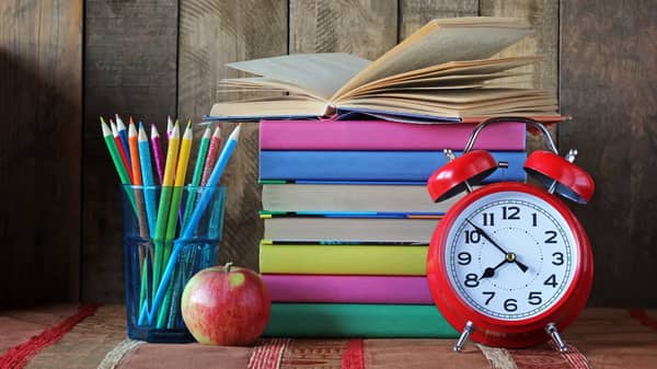 Alarm clock, pencils and a stack of books. Back to school.