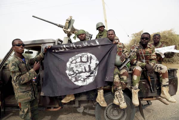 FILE PHOTO: Nigerian soldiers hold up a Boko Haram flag that they had seized in the recently retaken town of Damasak, Nigeria
