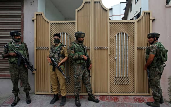 Indian policemen stand guard outside a house during a search operation after a shootout, in which a Central Reserve Police Force (CRPF) officer was killed, in Srinagar