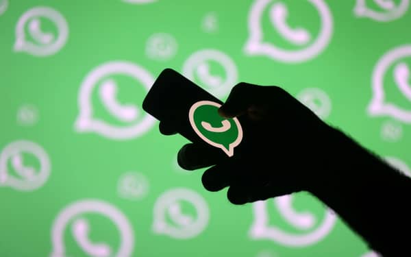FILE PHOTO: A man poses with a smartphone in front of displayed Whatsapp logo in this illustration