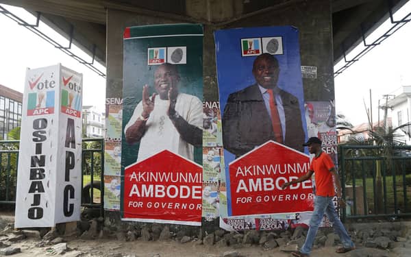 A man walks past banners campaigning for All Progressives Congress governorship candidate Akinwunmi Ambode, under a bridge in Lagos