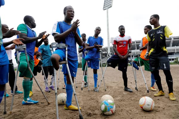 Nigeria’s national amputee football team gather to pray before the start of a training session in a bare field at the national stadium in Lagos