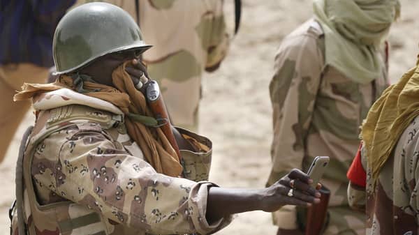 A Nigerien soldier covers his face while taking a picture of a mass grave in the recently retaken town of Damasak