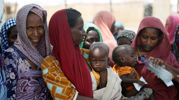 Women wait with their children under a shed for food rations at a internally displaced persons (IDP) camp on the outskirts of Maiduguri, northeast Nigeria