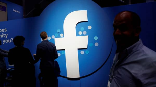 FILE PHOTO: Attendees walk past a Facebook logo during Facebook Inc’s F8 developers conference in San Jose