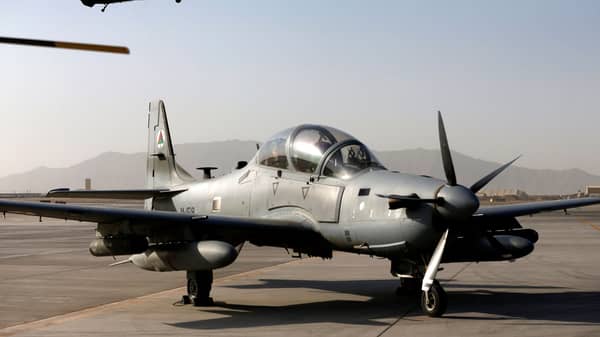 A Blackhawk helicopter flies above a parked A-29 Super Tucano aircraft, during a handover ceremony of Blackhawk helicopters from U.S. to the Afghan forces, at the Kandahar Air base