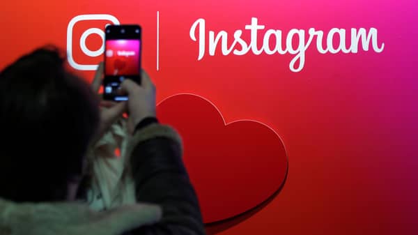 A visitor takes a picture of the Instagram application logo at the Young Entrepreneurs fair in Paris
