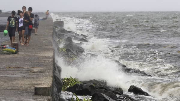 Youth walk on breakwater where rough waves caused by Typhoon Kalmaegi, also called Luis, are crashing, at Manila Bay