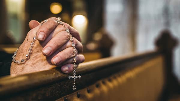 Praying hands with rosary in church