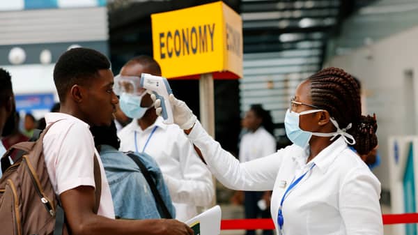 FILE PHOTO: A health worker checks the temperature of a traveller as part of the coronavirus screening procedure at the Kotoka International Airport in Accra,