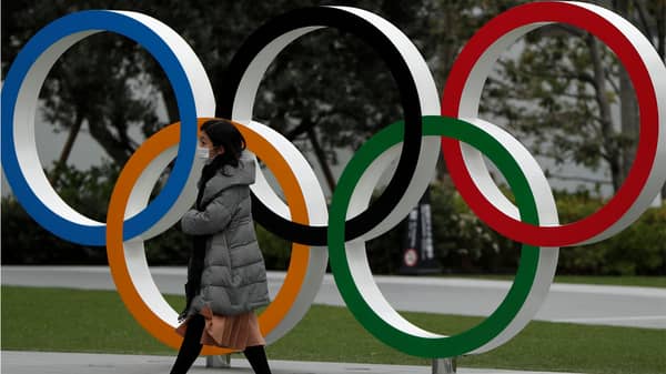A woman wearing a protective face mask, following an outbreak of the coronavirus disease, walks past the Olympic rings in front of the Japan Olympics Museum, in Tokyo