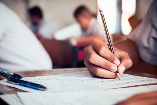 close-up-student-holding-pencil-writing-final-exam-examination-room-study-classroom-vintage-style_73622-242