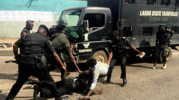 Police officers pull a journalist during an anti-government protest in Lagos