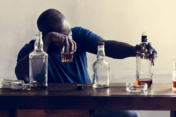 African descent man sitting drinking whiskey alcoholic addiction bad habit