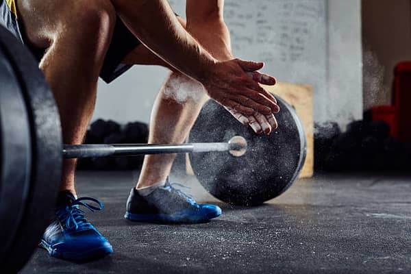 Closeup of weightlifter clapping hands before  barbell workout at the gym