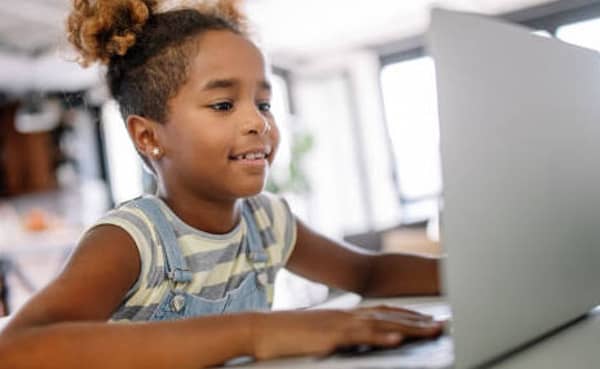 African kid girl spending time with notebook and modern technology