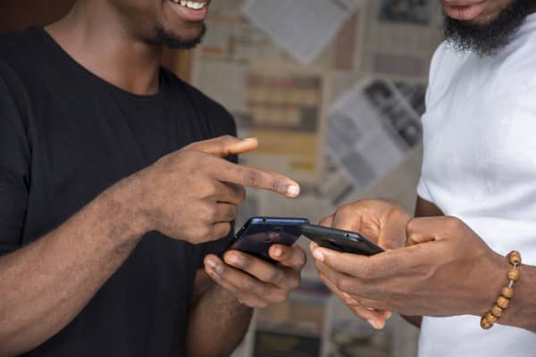 Closeup of two African males sharing content with their phones