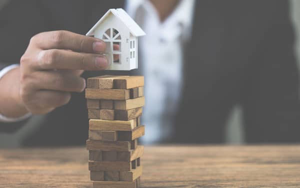 Businessman hand holding model white house on wood block. Invest