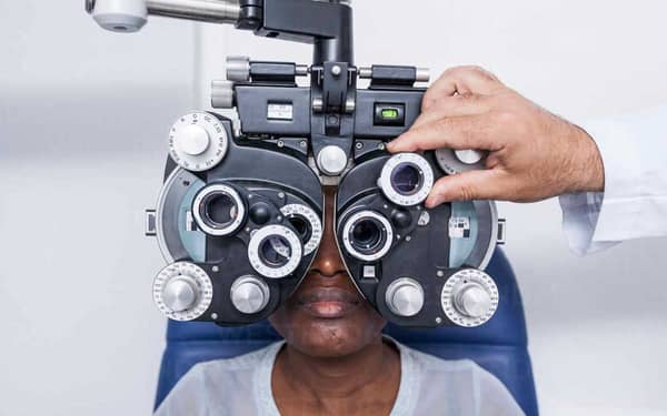 Optometrist-adjusting-the-optometry-equipment-during-study-of-the-eyesight-of-a-black-woman-ADSF28784