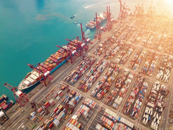 Aerial top view of container cargo ship in the export and import business and logistics international goods in urban city. Shipping to the harbor by crane in Victoria Harbour, Hong Kong.