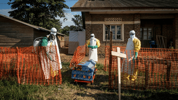 Medical workers disinfect the coffin of a deceased unconfirmed Ebola patient