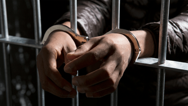 Handcuffed inmate behind bars