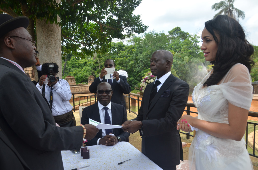 The officiating minister hands the marriage certificate to the Comrade Governor