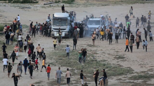 Palestinians rush trucks as they transport international humanitarian aid from the US-built Trident Pier near Nuseirat in the central Gaza Strip on May 18, 2024, amid the ongoing conflict between Israel and the militant group Hamas. (Photo by AFP)