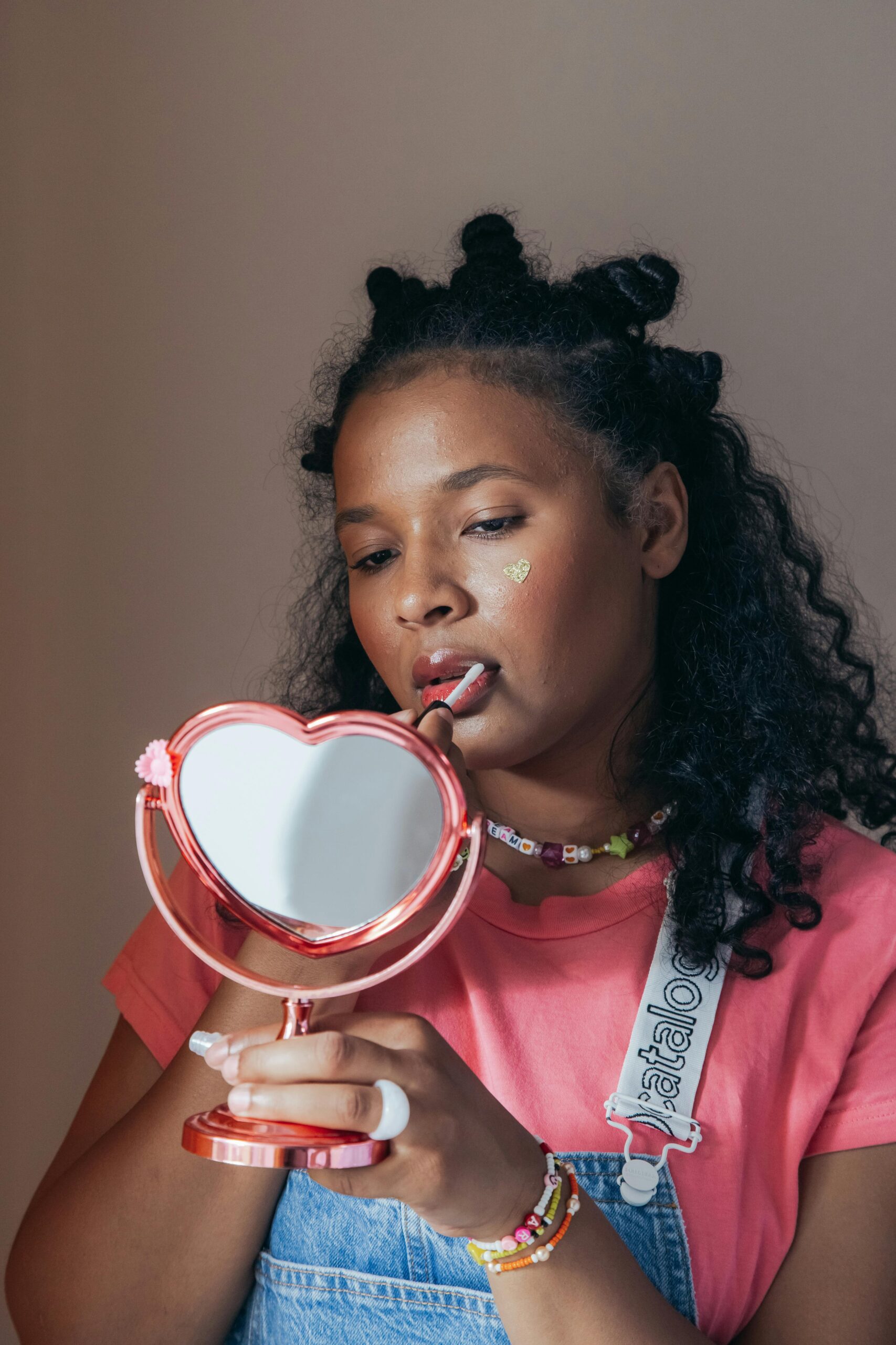 Woman applying makeup while holding a mirror